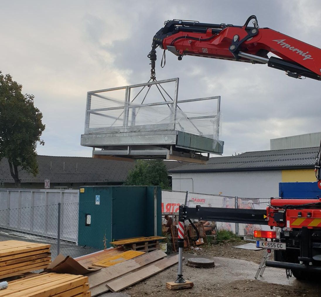 A crane lifts a loading platform onto a construction site.