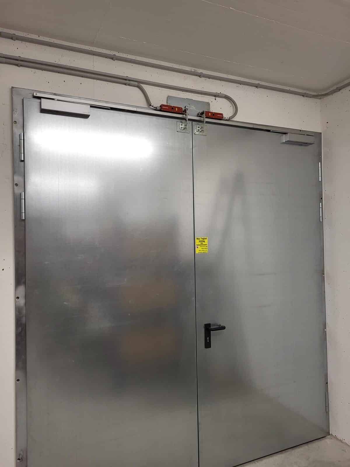 A metal door in a garage with a heavy duty lift table attached to it.