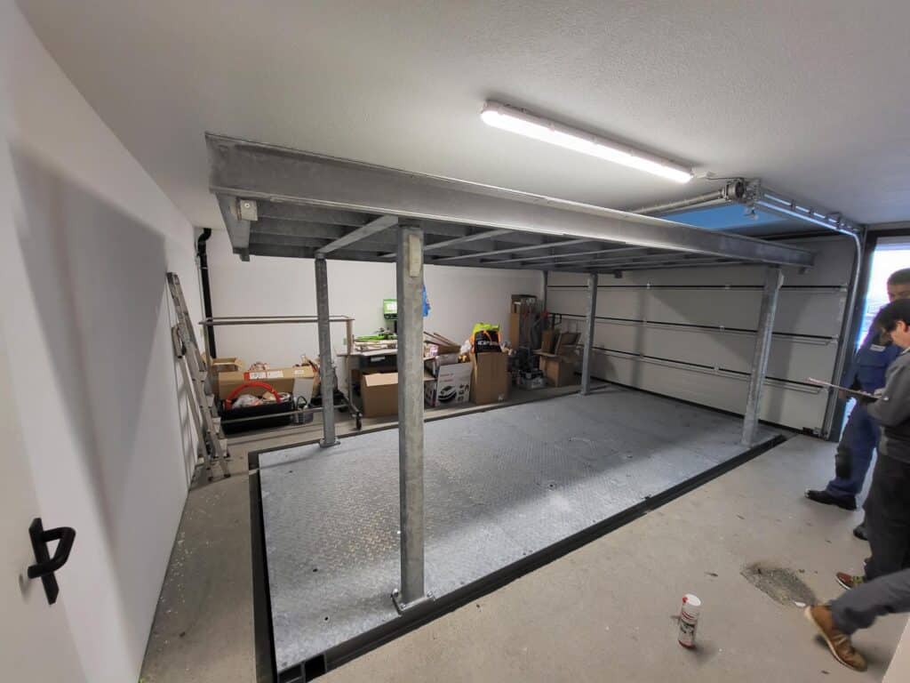 A garage with two people standing next to a heavy-duty lift table.